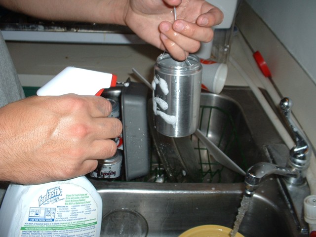 Cleaning the shakers at the sink using spray cleaner.